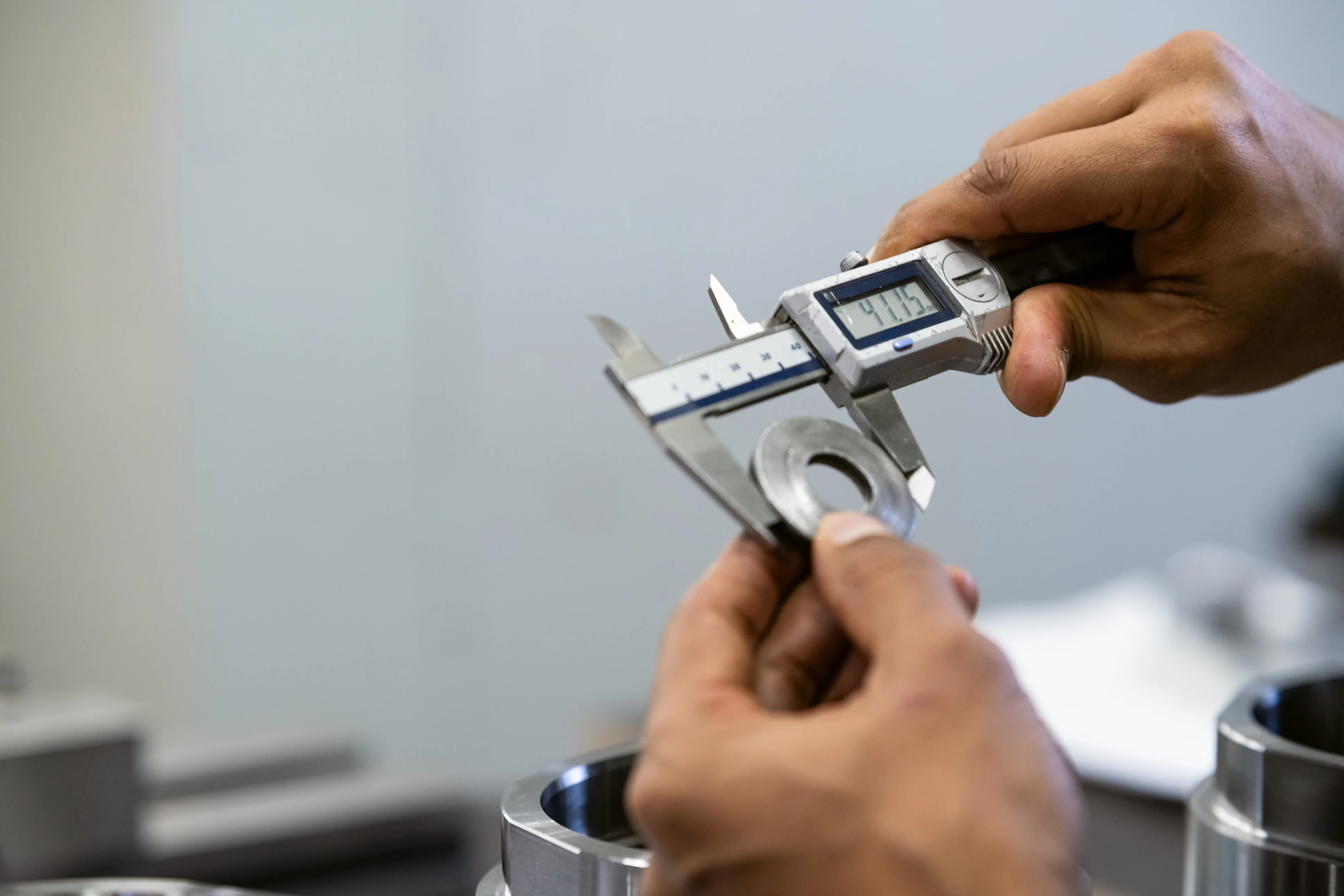 Digital callipers measuring a precision machined hydraulic component — dimensional verification at reassembly