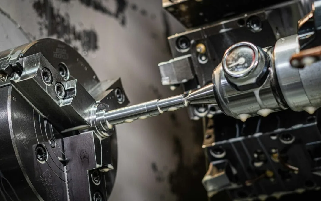 CNC lathe turning a precision metal shaft — chuck and cutting tool visible