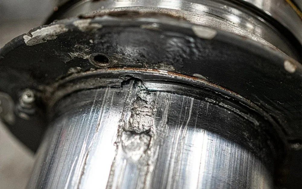 Close-up of scored and corroded hydraulic rod surface before restoration
