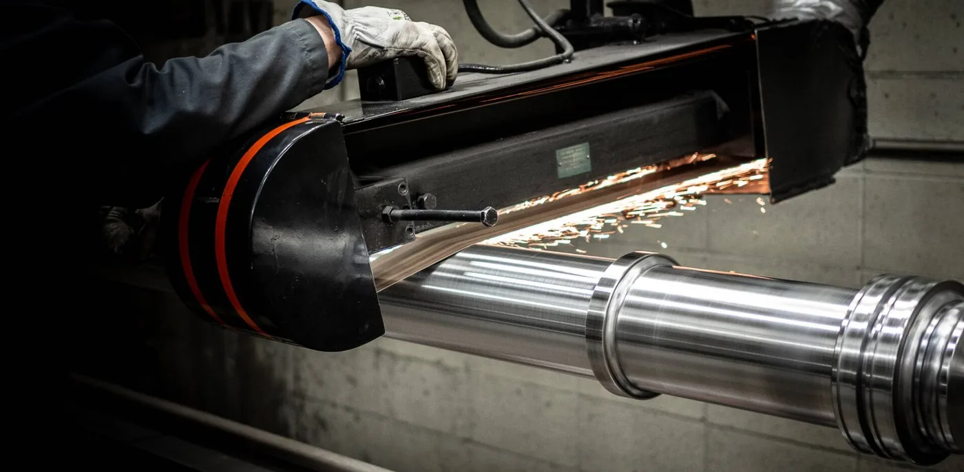 Hydraulic rod being cylindrically ground — grinding sparks visible